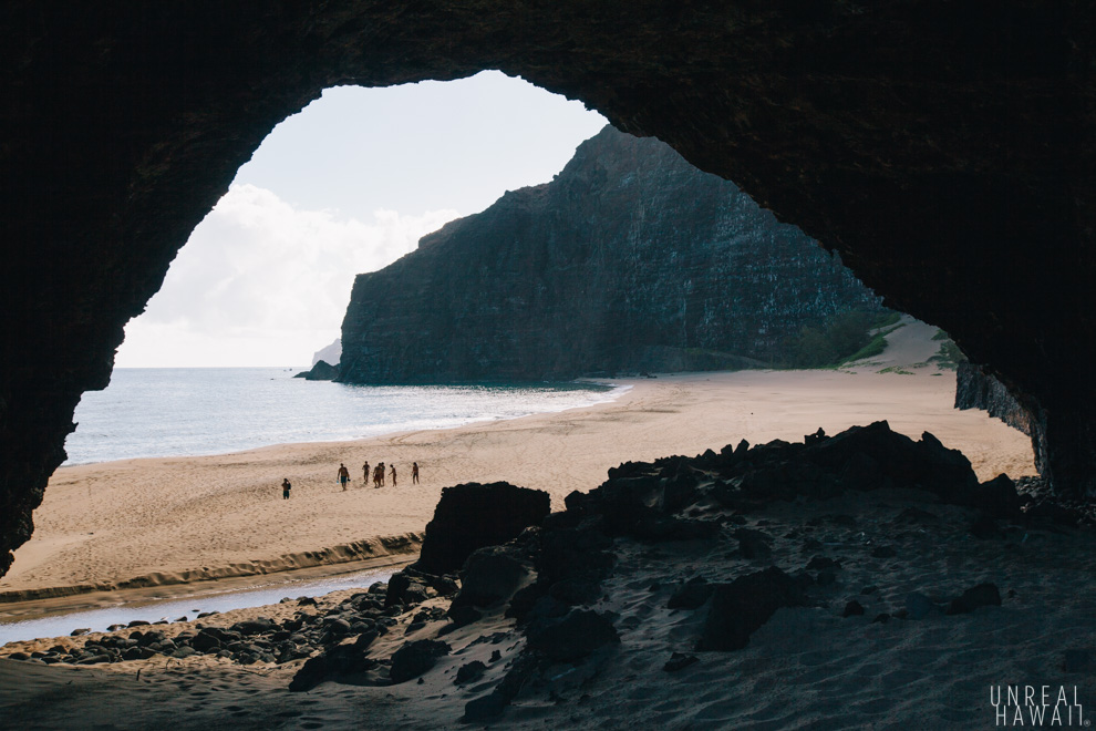 People walk under the arch at Honopu Beach, Kauai, Hawaii